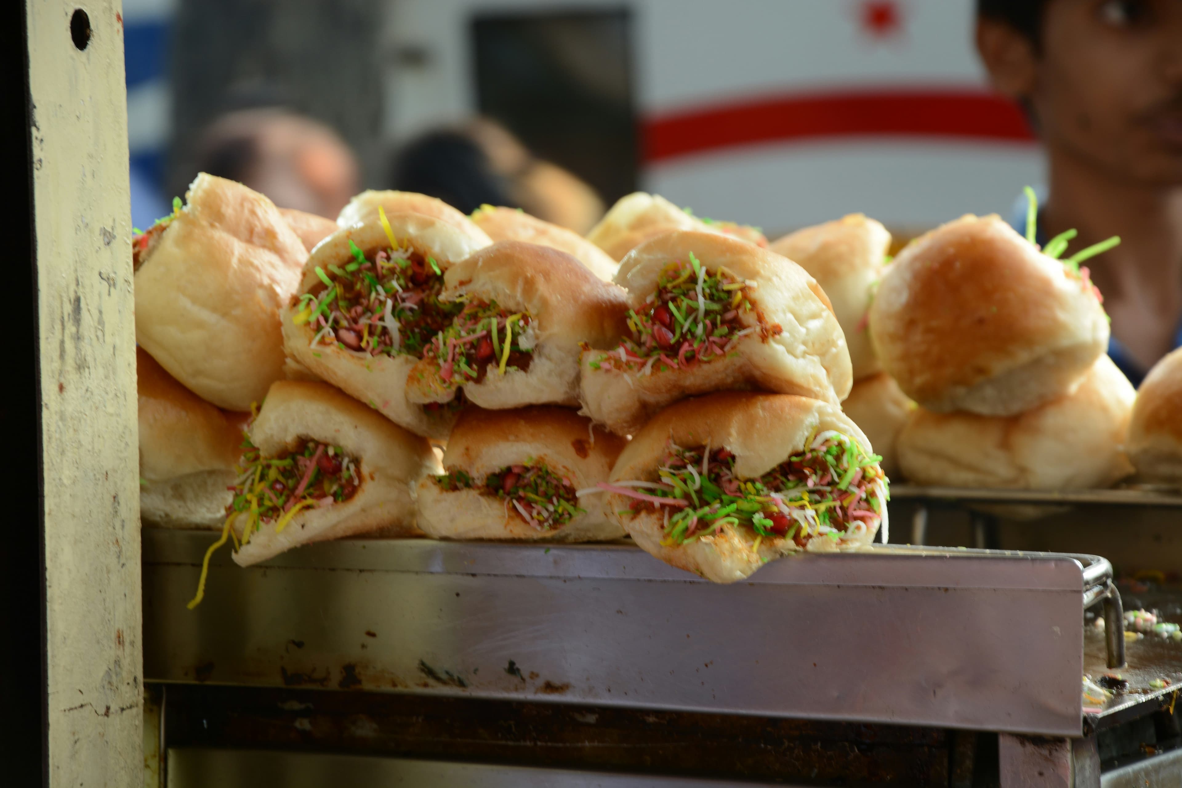 Kacchi Dabeli — a sweet and spicy potato stuffed pav garnished with pomegranate seeds, sev, and roasted peanuts, a popular street snack in Pune